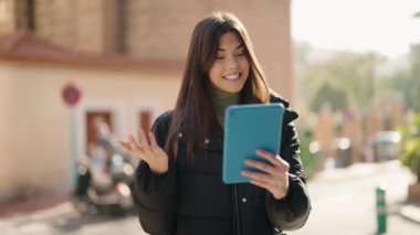 Young hispanic woman smiling confident having video call at street