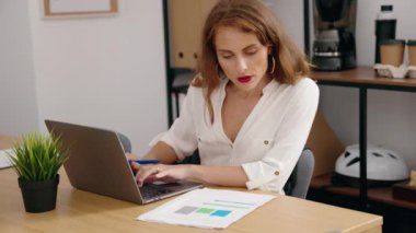 Young beautiful hispanic woman business worker using laptop reading document at office