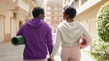 African american man and woman couple holding yoga mat walking at street