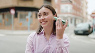 Young hispanic woman smiling confident listening audio message by the smartphone at street