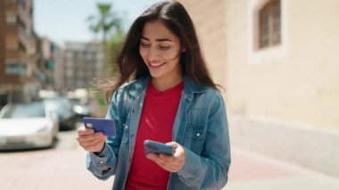 Young hispanic girl using smartphone and credit card at street