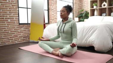 African american woman training yoga sitting on floor at bedroom