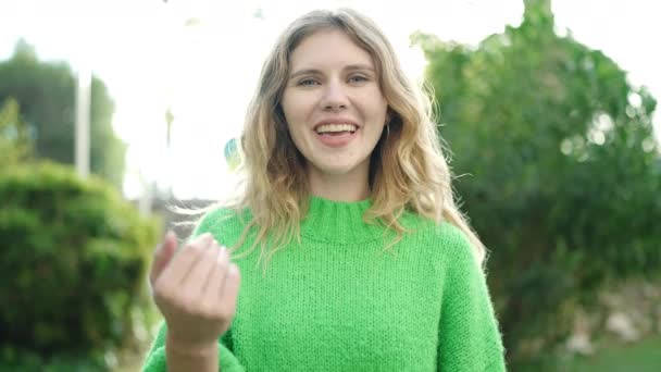 Young Blonde Woman Smiling Confident Doing Coming Gesture Hand Park — Vídeo de Stock