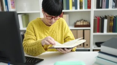 Young chinese woman student reading book studying at library university