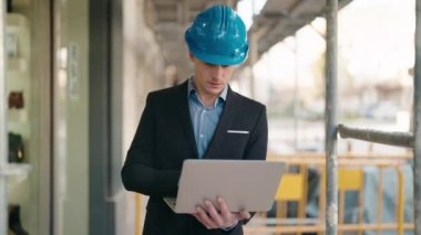 Young caucasian man architect with relaxed expression using laptop at street