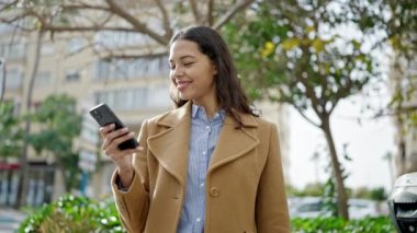 Genç, güzel İspanyol kadın parkta akıllı telefondan müzik dinliyor.