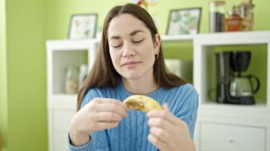 Beyaz bir kadın yemek masasında muz yiyor.