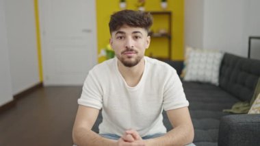 Genç Arap adam evdeki kanepede kendinden emin bir şekilde oturuyor.