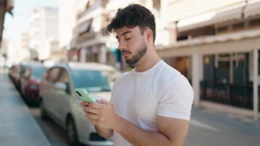 Sokakta akıllı telefon kullanan, kendine güvenen genç bir İspanyol.