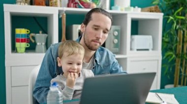 Baba ve oğul yemek odasında çalışıyor ve çocuğa bakıyor.