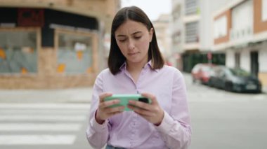Sokakta akıllı telefon kullanan, kendine güvenen genç İspanyol kadın.