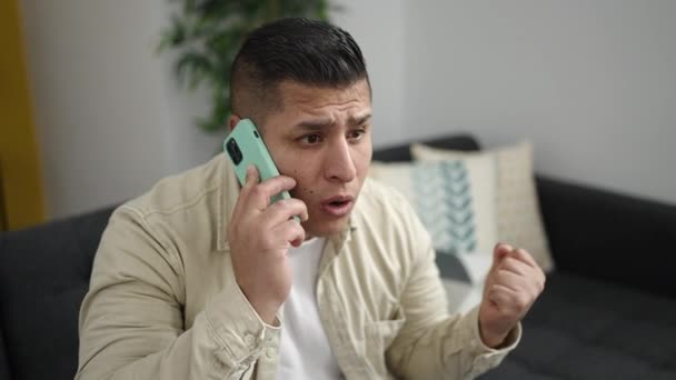 Joven Hombre Hispano Hablando Teléfono Inteligente Sentado Sofá Mirando Molesto — Vídeos de Stock