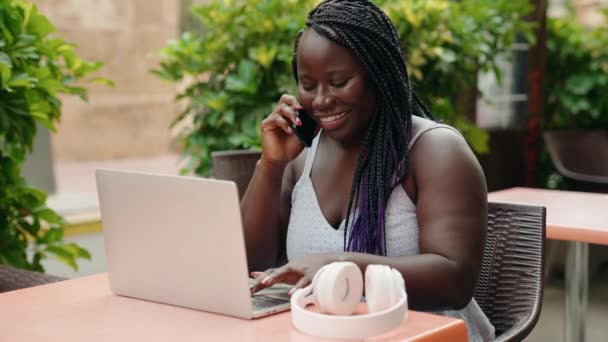 Africano Americano Mulher Falando Smartphone Usando Laptop Sentado Mesa Terraço — Vídeo de Stock
