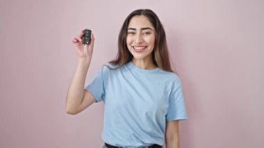 Genç ve güzel İspanyol kadın gülümsüyor. Kendine güveni tam. Yeni arabanın anahtarına işaret ediyor.