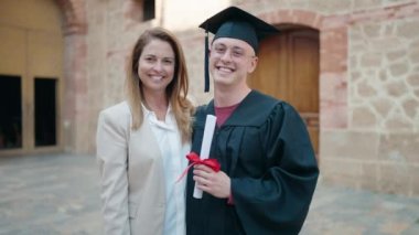 Man and woman mother and son hugging each other celebrating graduation at university