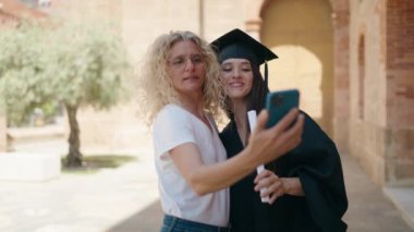 İki kadın anne ve mezun kız kampüs üniversitesinde akıllı telefondan selfie çekiyorlar.