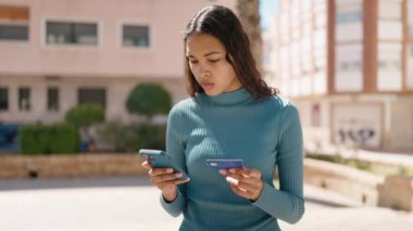 Genç Afrikalı Amerikalı kadın akıllı telefon ve kredi kartı kullanıyor.