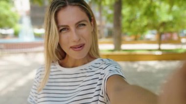 Young blonde woman smiling confident having video call at park