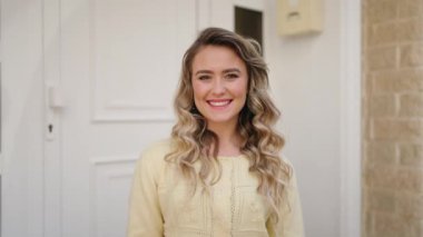 Genç sarışın kadın gülümsüyor. Anahtarı elinde tutuyor.