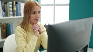Young blonde woman student using computer stressed at university classroom