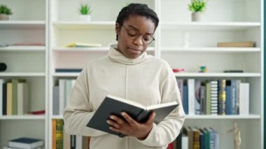 Afrikalı Amerikalı öğrenci kitap okuyor. Kütüphanede sessizlik istiyor.