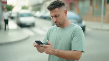 Genç İspanyol adam akıllı telefon kullanıyor. Sokakta ciddi bir ifadesi var.