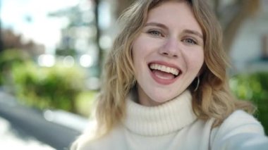 Young blonde woman smiling confident having video call at park