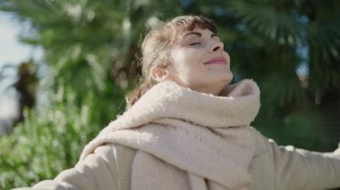 Young caucasian woman smiling confident with closed eyes enjoying sunlight at park