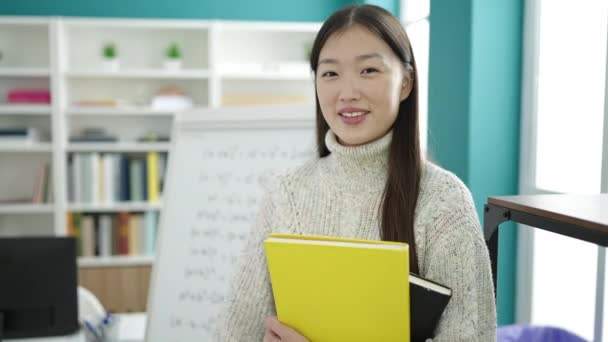 若いです中国人女性学生保持本とともに指差しでカメラに図書館大学 — ストック動画