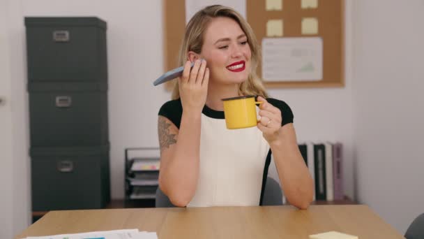 若い美しいヒスパニック系女性ビジネスワーカーがオフィスでスマートフォンのコーヒーを飲むことで音声メッセージを聞く — ストック動画