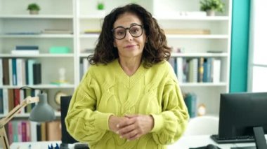 Orta yaşlı İspanyol kadın öğretmen kütüphane üniversitesinde belirsiz bir ifade veriyor.