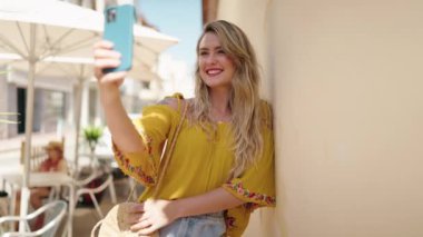 Young woman smiling confident making selfie by the smartphone at street
