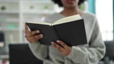 African american woman student reading book doing silence gesture at library university