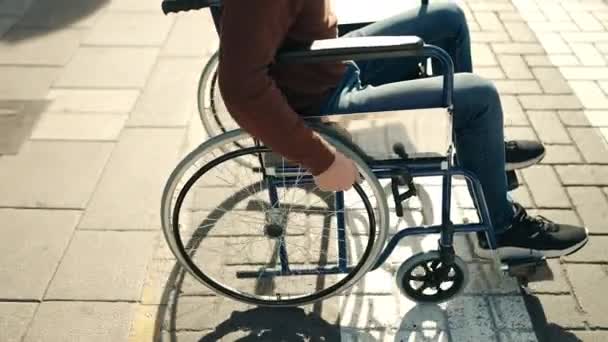 年轻的惊慌失措的男人骑着轮椅在街上走着 — 图库视频影像
