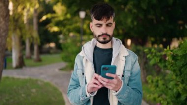Parkta akıllı telefon kullanan ciddi yüzlü İspanyol bir genç.