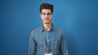 Genç İspanyol güler yüzlü, kendine güvenen, el kol hareketleri yapan, izole edilmiş mavi arka planı olan bir adam.