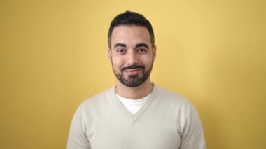 Young hispanic man smiling confident standing over isolated yellow background