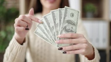 Young beautiful hispanic woman business worker counting dollars at office
