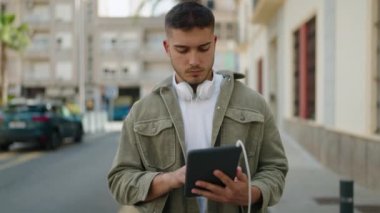 Young hispanic man using touchpad at street