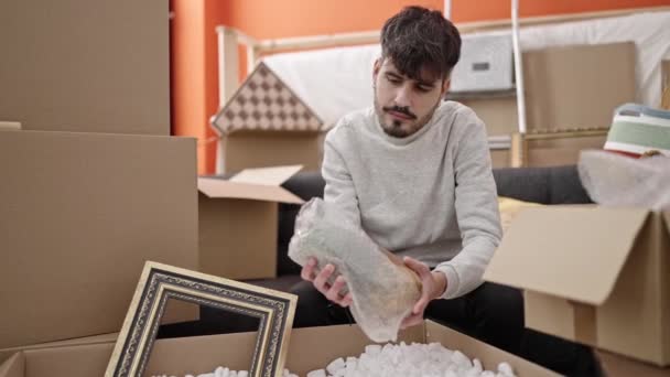 Young Hispanic Man Unpacking Cardboard Box New Home — Stockvideo