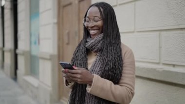 African woman smiling using smartphone at street