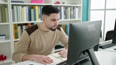 Genç Arap erkek öğrenci üniversite sınıfında bilgisayarla çalışmaktan yoruldu.
