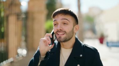 Genç İspanyol adam gülümsüyor. Kendine güveniyor. Sokakta akıllı telefondan konuşuyor.