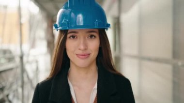 Young hispanic woman architect standing with arms crossed gesture at street
