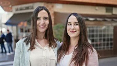 Kahve dükkanının terasında kendine güvenen iki kadın.