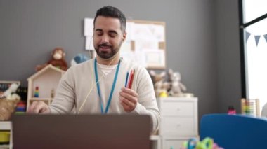 Young hispanic man on a video call working as teacher at kindergarten