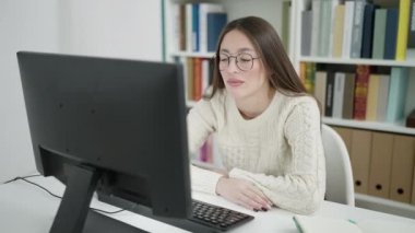 Young beautiful hispanic woman student using computer stressed at library university