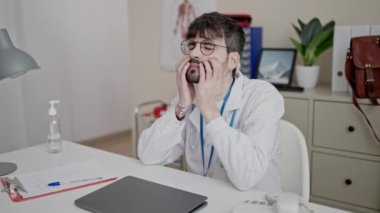 Young hispanic man doctor stressed working at clinic