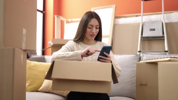 Mujer Hispana Hermosa Joven Usando Teléfono Inteligente Desembalaje Caja Cartón — Vídeo de stock