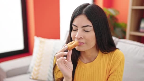 Young Beautiful Hispanic Woman Eating Doughnut Sitting Sofa Home — Stock Video